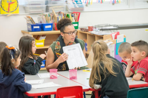 Teacher guiding young students in completing handout